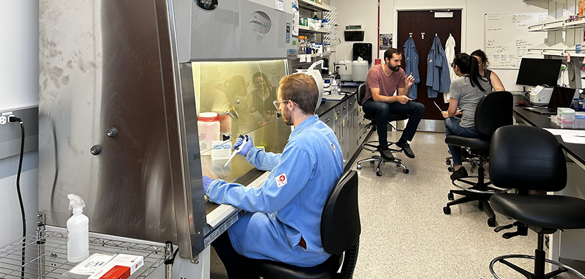 A person in blue scrubs working in a laboratory